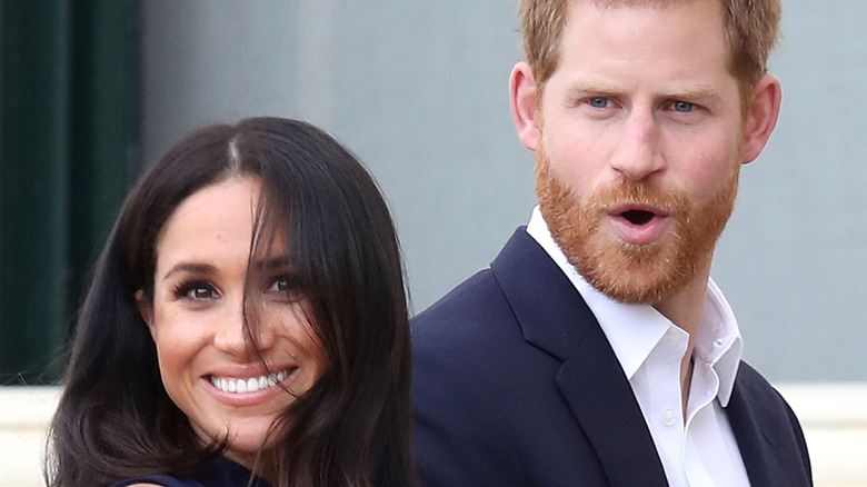 Meghan Markle smiles while Prince Harry looks shocked