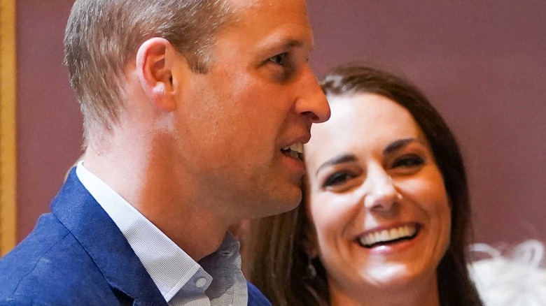 Prince William and Kate Middleton smile at an event. 