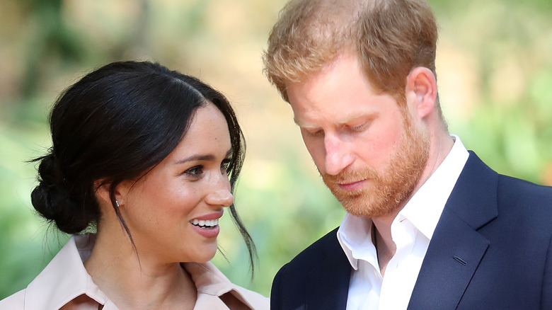 Meghan Markle smiles while Prince Harry looks down