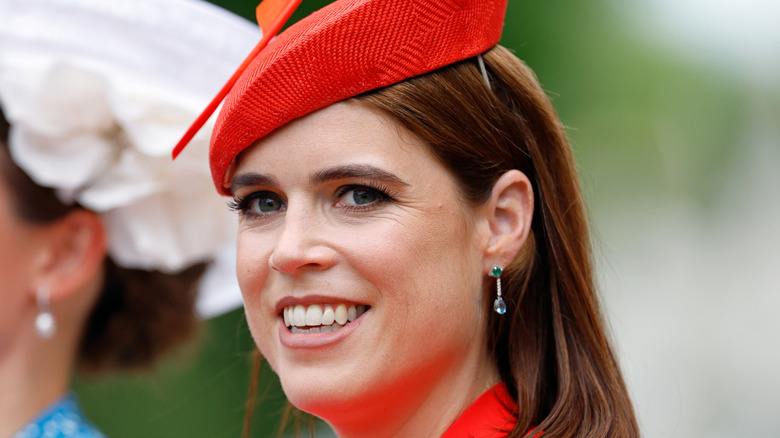 Princess Eugenie in red fascinator and emerald-aquamarine drop earrings