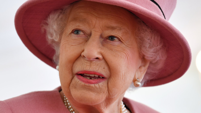 Queen Elizabeth smiling under a pink hat