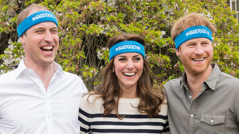 Prince William, Kate Middleton, and Prince Harry smiling while wearing matching headbands