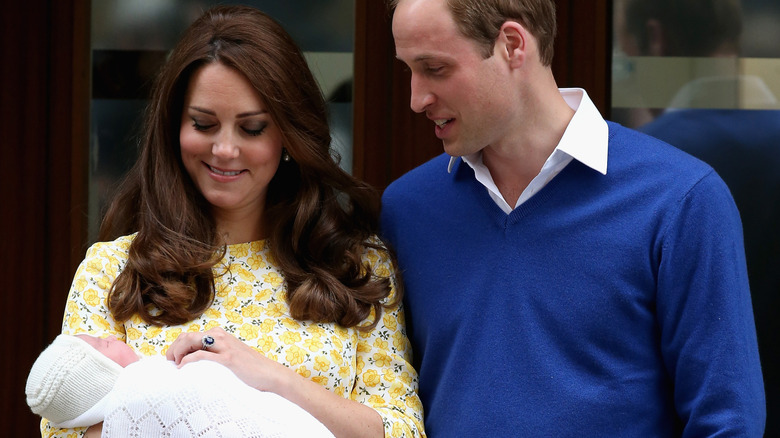 A smiling Princess Catherine and Prince William in front of St. Mary's Hospital's Lindo Wing with Princess Charlotte