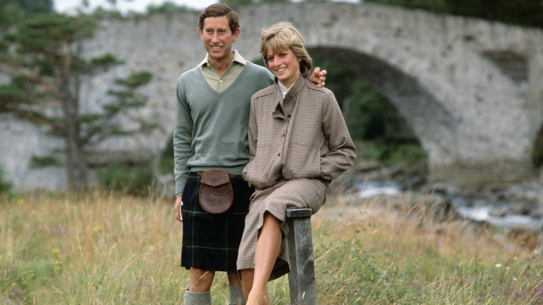 Prince Charles and Princess Diana posing for a photo in a field next to a river