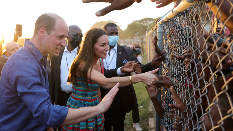Prince William and Princess Catherine greeting children behind a fence