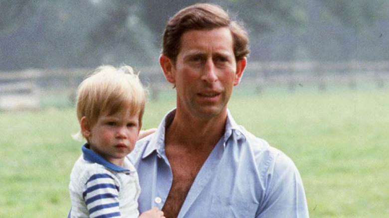 Prince Charles holding a toddler Prince Harry