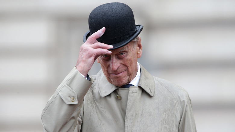 An elderly Prince Philip removing his cap