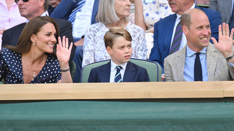 Prince George sitting between Princess Catherine and Prince William at Wimbledon