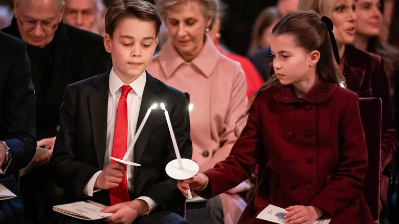 Prince George and Princess Charlotte lighting a candle togethe
