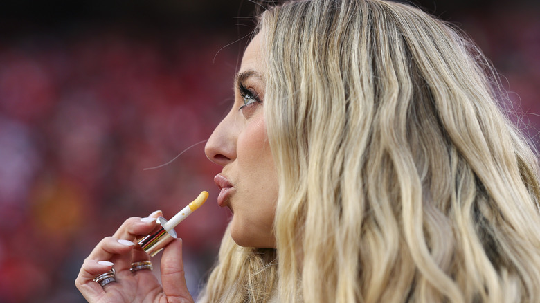 Brittany Mahomes puckering her lips as she applies lip gloss