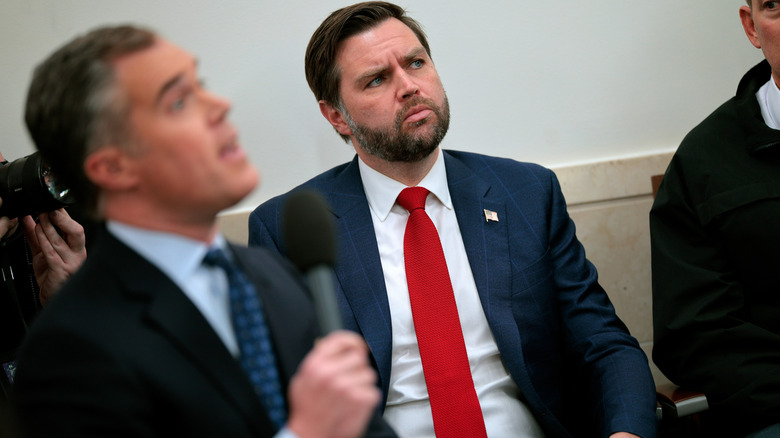 JD Vance looking concerned in a navy suit with a red tie