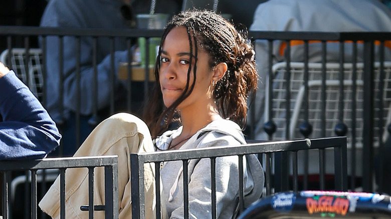 Malia Obama sitting outside looking down paparazzi camera
