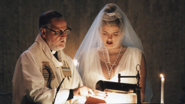 Anna Nicole Smith reading at the alter with a priest at her husband's memorial service