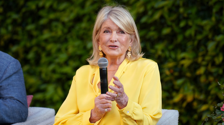 Martha Stewart speaking into a microphone in a yellow blouse