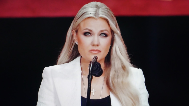 Erika Kirk at microphone looking solemn