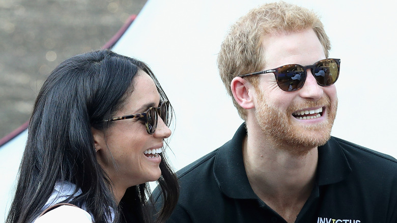 Meghan Markle and Prince Harry smiling while wearing sunglasses