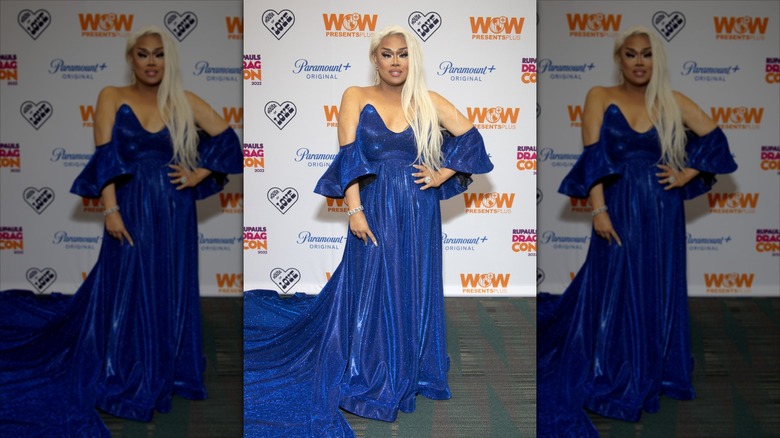 A blonde Jiggly Caliente on a WOW step-and-repeat, in a flowing blue gown