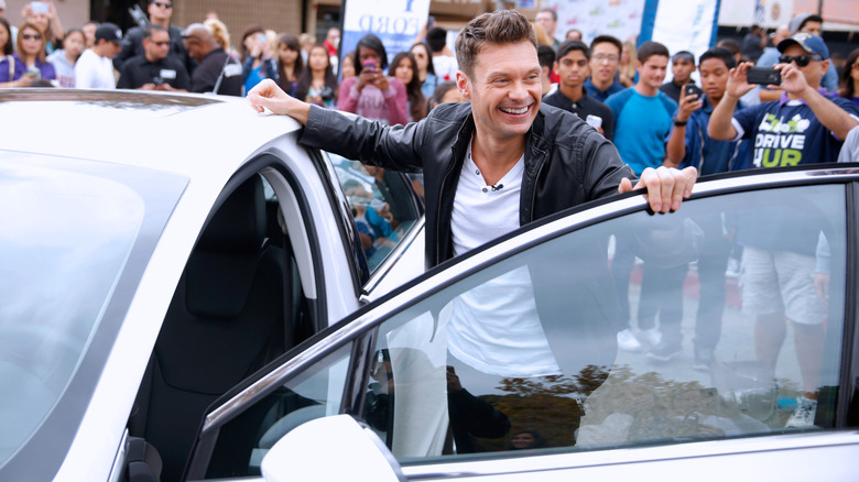 Ryan Seacrest smiling while getting inside a car