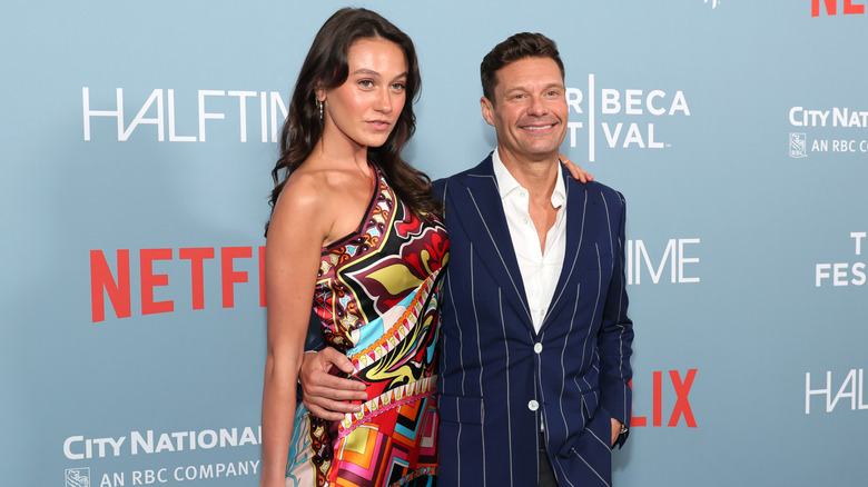 Aubrey Paige and Ryan Seacrest posing together on a red carpet