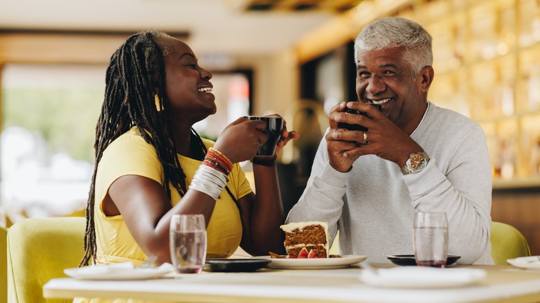 A couple laughing and drinking coffee