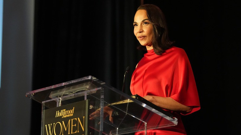 Amanda Brugel giving a speech in a red dress
