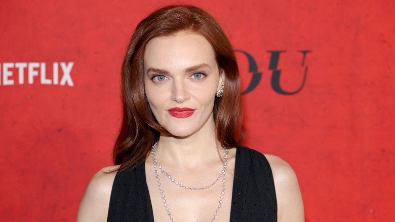 Madeline Brewer posing in a black dress with red lipstick