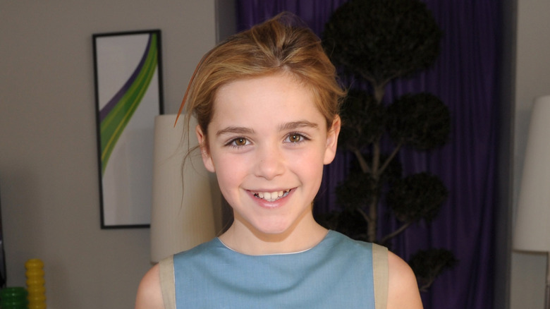 A young Kiernan Shipka smiling in a light blue dress