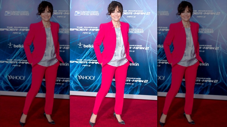 Sally Field smiling with her hands in her pockets in a hot pink suit