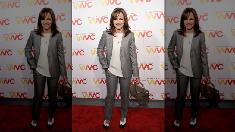 Sally Field smiling with her hand in her pocket in a grey suit