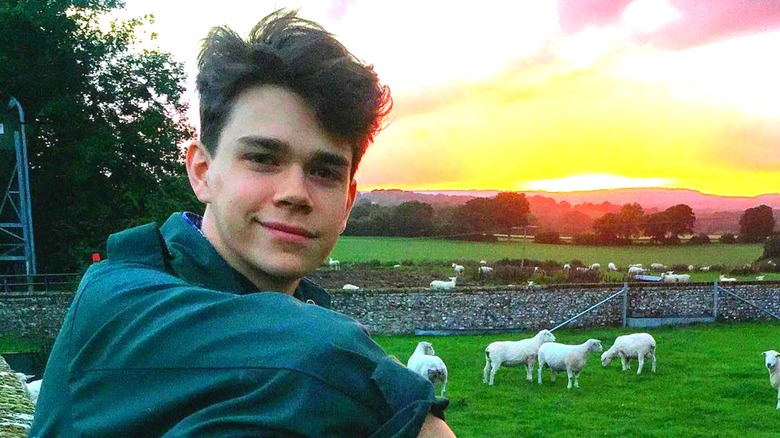 Samuel Chatto posing in front of field with sheep