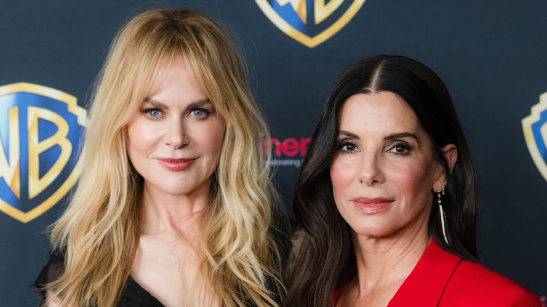 Nicole Kidman in black and Sandra Bullock in red against WB background