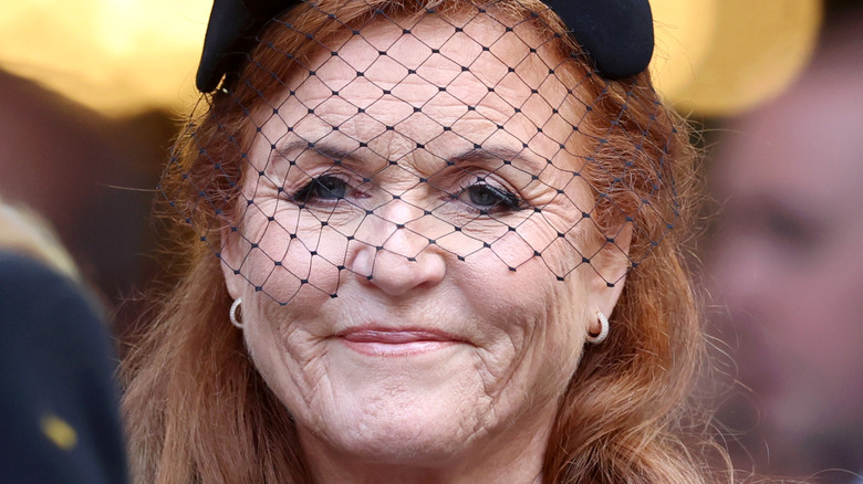 Sarah Ferguson smiling while wearing a black hat with a matching face veil
