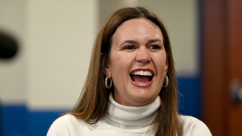 Sarah Huckabee Sanders laughing in a white turtleneck