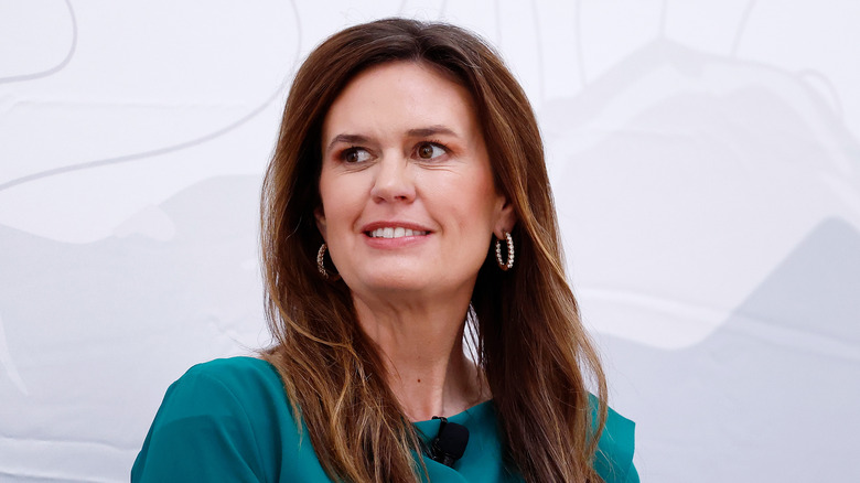 Sarah Huckabee Sanders smiling while wearing a green dress.