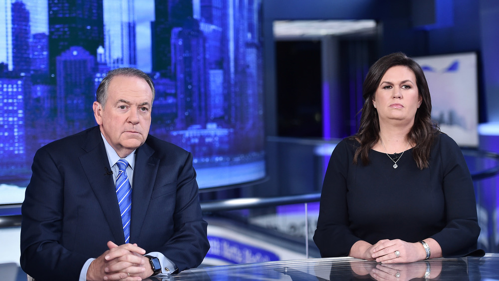 Mike Huckabee and Sarah Huckabee Sanders sitting at desk