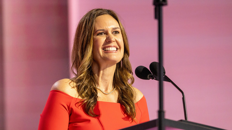 Sarah Huckabee Sanders smiling behind podium