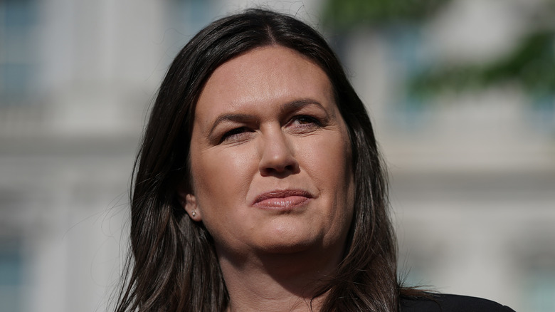 Sarah Huckabee Sanders wearing a black shirt while talking to reporters outside the White House.