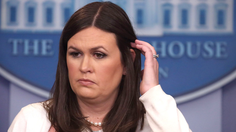 Sarah Huckabee Sanders looking mad and tucking her hair behind her ear
