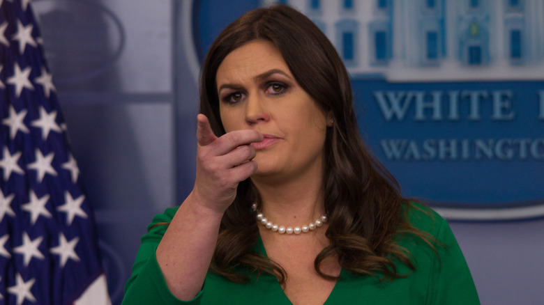 Sarah Huckabee Sanders pointing in a green dress and pearls