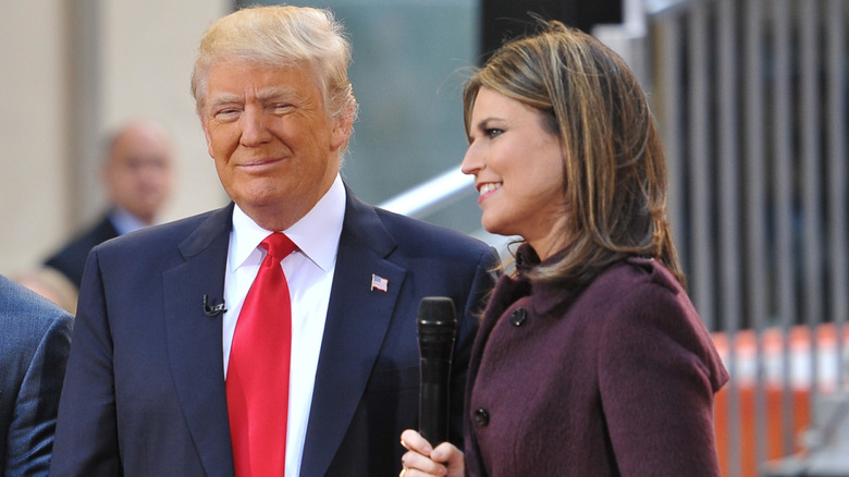Donald Trump in a blue suit and red tie, Savanah Guthrie wearing a coat and holding a microphone