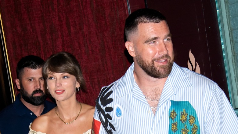 Taylor Swift and Travis Kelce smiling and walking