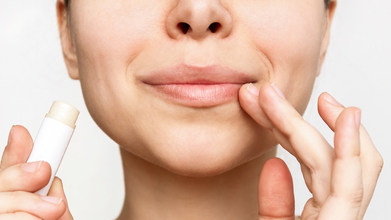 woman touching dry lips holding chapstick