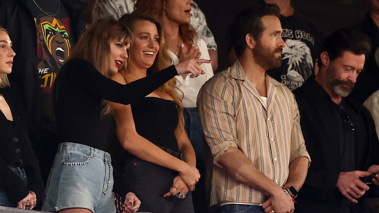 Taylor Swift pointing to something with Blake Lively and Ryan Reynolds