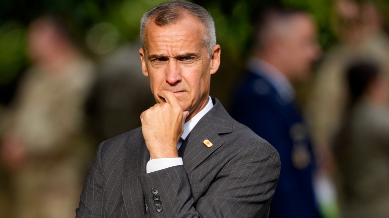 Corey Lewandowski looking worried in a grey pinstripe suit with a finger to his lip