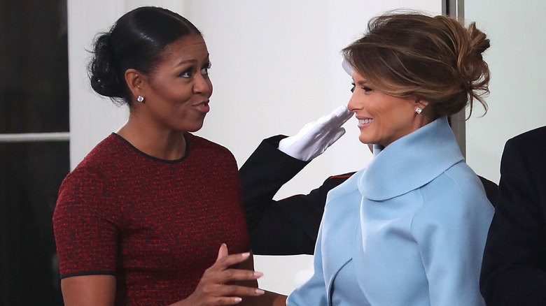 Melania Trump smiling at Michelle Obama talking