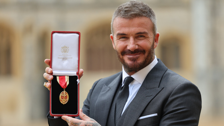 image of David Beckham holding up an award and smiling