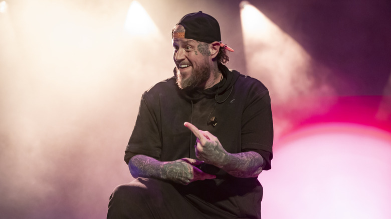 Jelly Roll on stage wearing black and a backwards baseball cap