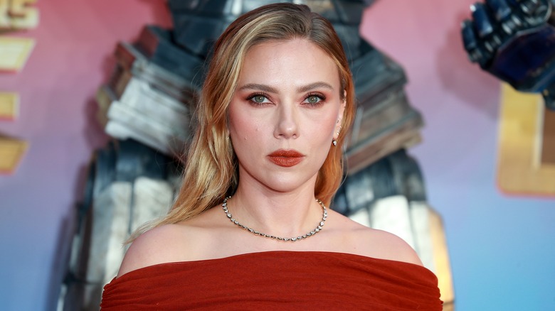 Scarlett Johansson posing in a red off the shoulder dress