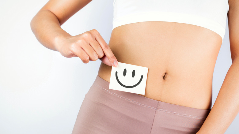 Woman holding a smiley face next to her stomach