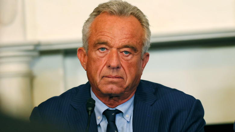 RFK Jr. sporting an orange glow while frowning in a blue suit
